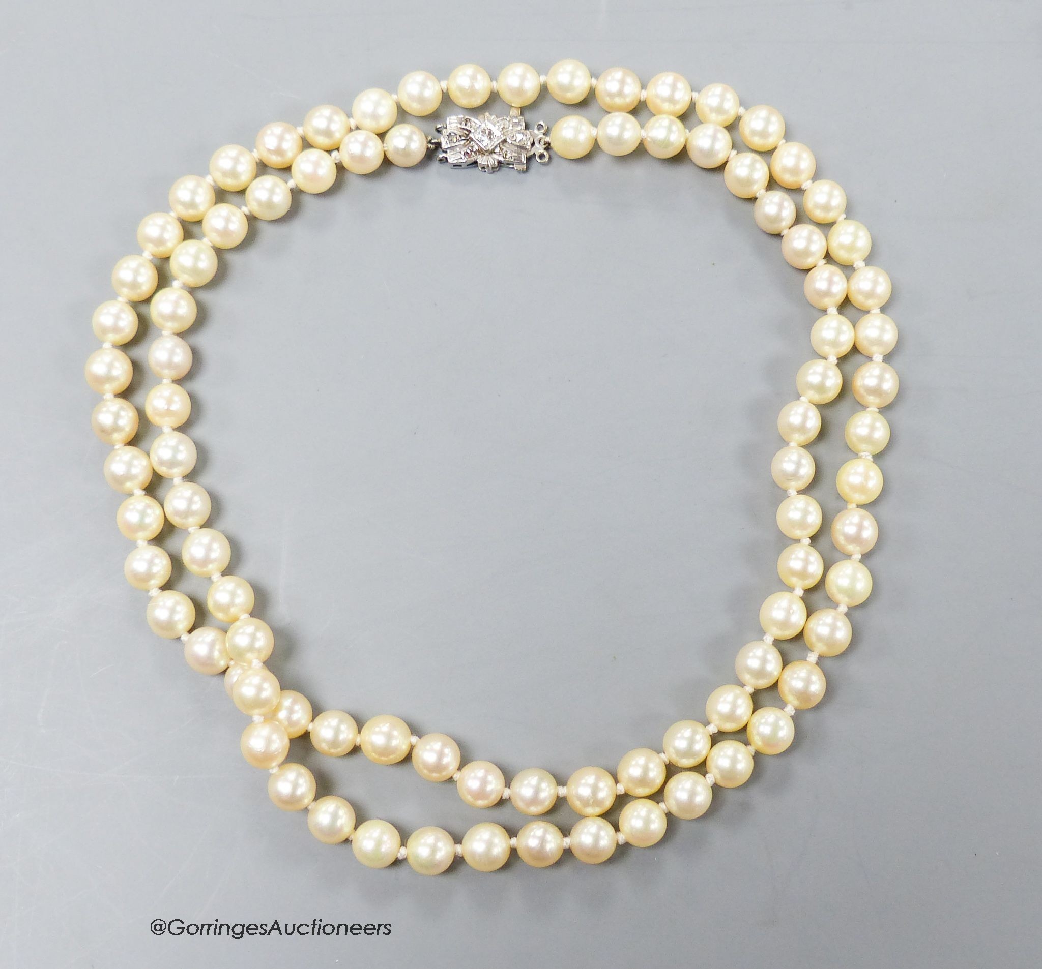 A single strand cultured pearl necklace, with 18ct white metal and diamond set bow clasp, 72cm, gross 47.6 grams.